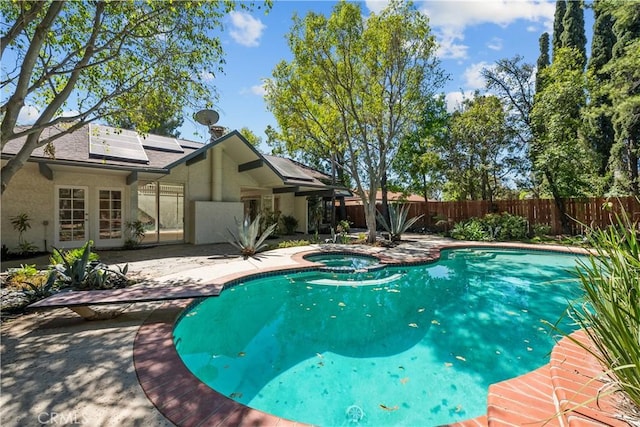 view of pool featuring french doors, a patio area, a fenced backyard, and a pool with connected hot tub
