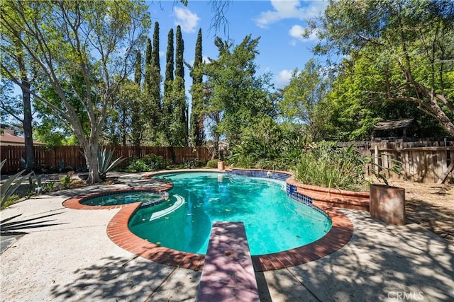view of pool with a fenced backyard and a pool with connected hot tub