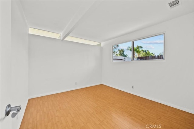 spare room featuring visible vents, baseboards, and wood finished floors