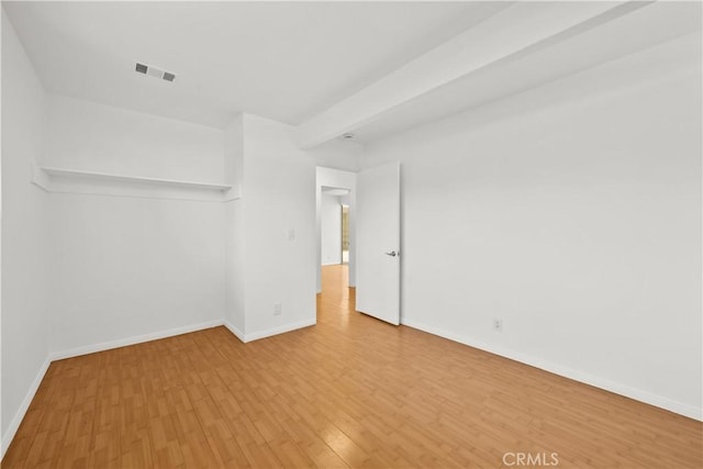 empty room featuring visible vents, baseboards, and wood finished floors