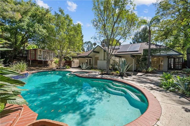 pool with a patio area, french doors, and an outbuilding
