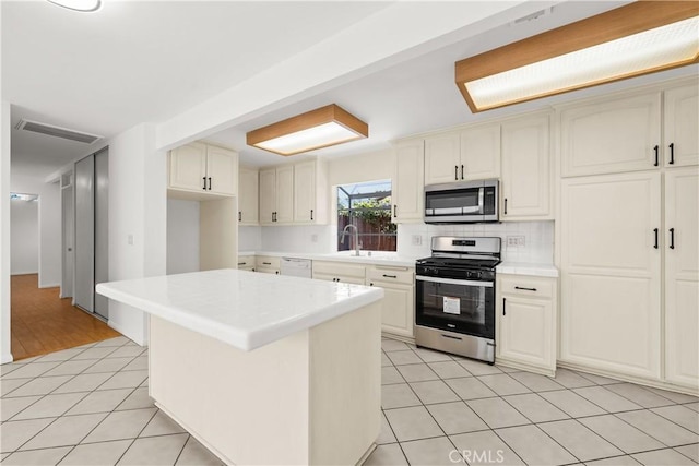 kitchen featuring light tile patterned floors, visible vents, light countertops, stainless steel appliances, and decorative backsplash