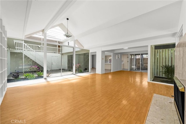 interior space with wood finished floors, beamed ceiling, and high vaulted ceiling