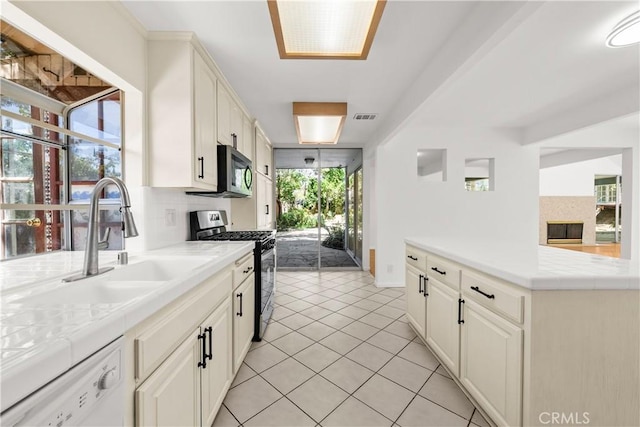 kitchen featuring tasteful backsplash, visible vents, gas stove, a sink, and white dishwasher