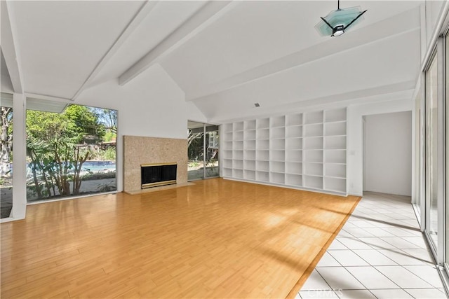 unfurnished living room featuring light wood-style flooring, built in features, a wealth of natural light, and lofted ceiling with beams