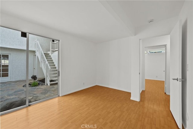 empty room with stairway, baseboards, and wood finished floors