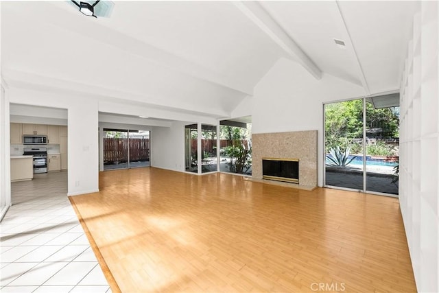 unfurnished living room featuring visible vents, light wood finished floors, a fireplace, and beam ceiling