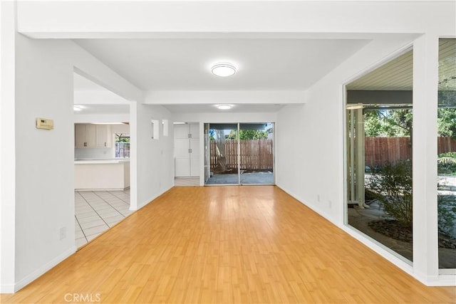 empty room featuring light wood-style floors, baseboards, and plenty of natural light