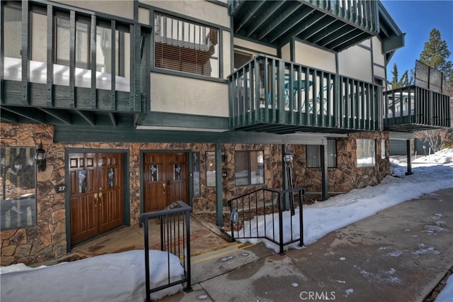 39802 Lakeview Dr Unit 26, Big Bear Lake, CA 92315 - snow covered property entrance with stucco siding, stone siding, and a balcony