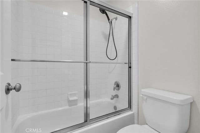 full bathroom featuring toilet and shower / bath combination with glass door