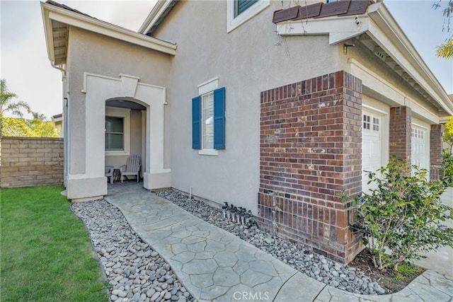 view of side of property with brick siding, stucco siding, and an attached garage
