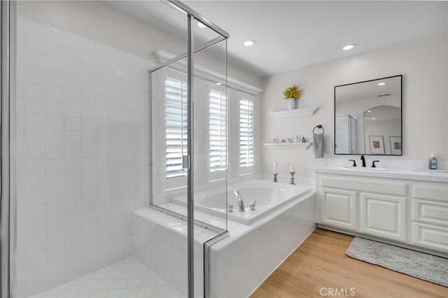 full bath with vanity, a shower stall, a garden tub, and wood finished floors