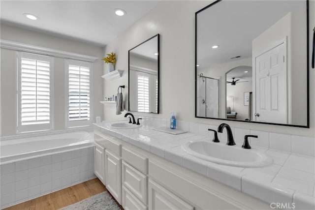 full bath featuring wood finished floors, a sink, a shower stall, and visible vents