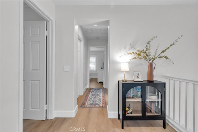 hall featuring baseboards, visible vents, and wood finished floors