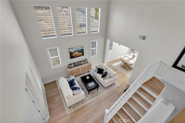 living room with baseboards, a high ceiling, visible vents, and wood finished floors