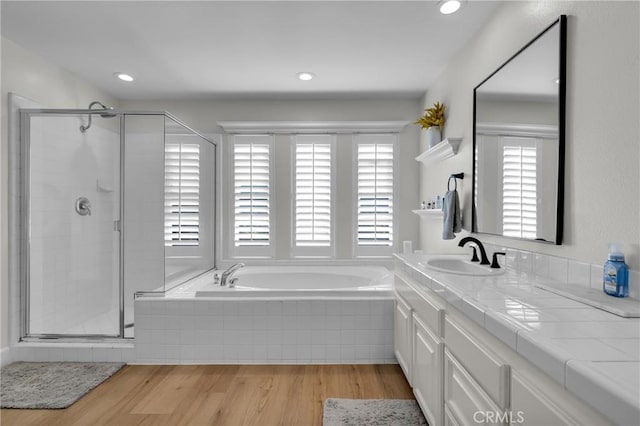 bathroom featuring a stall shower, wood finished floors, vanity, and a bath