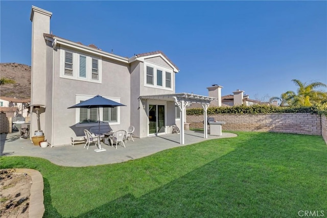 back of house with a pergola, stucco siding, a patio area, and a yard