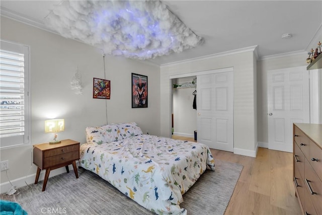bedroom with a closet, baseboards, light wood-style floors, and crown molding