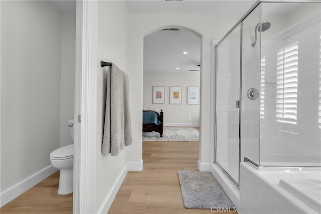ensuite bathroom with toilet, a shower stall, baseboards, and wood finished floors