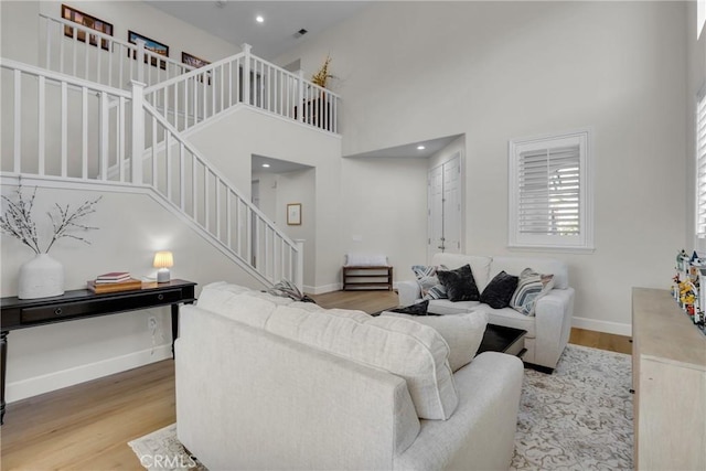 living room with baseboards, a high ceiling, wood finished floors, and stairway
