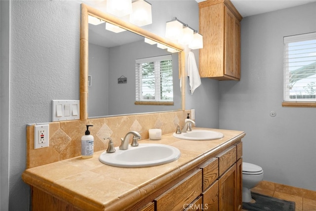 full bath with toilet, double vanity, a sink, and tile patterned floors