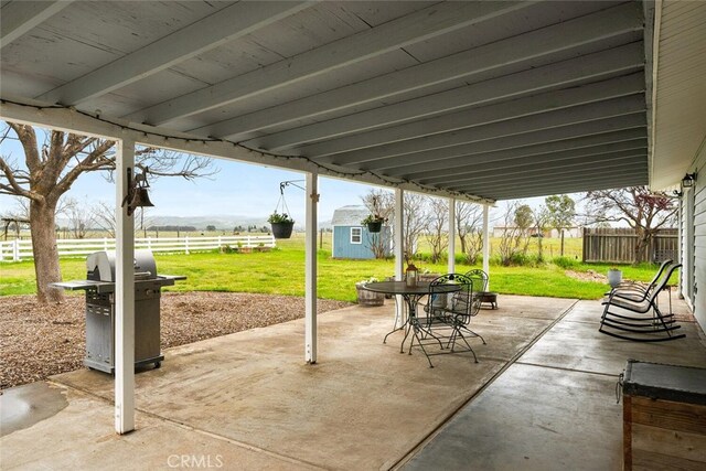 view of patio / terrace featuring a shed, an outbuilding, a fenced backyard, a rural view, and grilling area