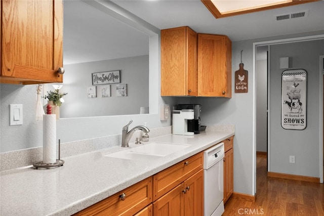 kitchen with light countertops, a sink, light wood finished floors, white dishwasher, and visible vents