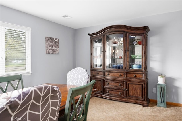 dining room featuring light colored carpet, visible vents, and baseboards
