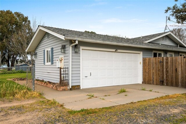 view of side of home with driveway, a garage, and fence