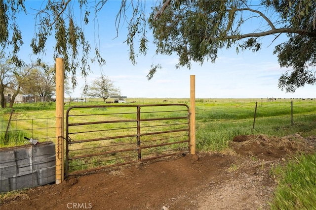view of gate with fence and a rural view