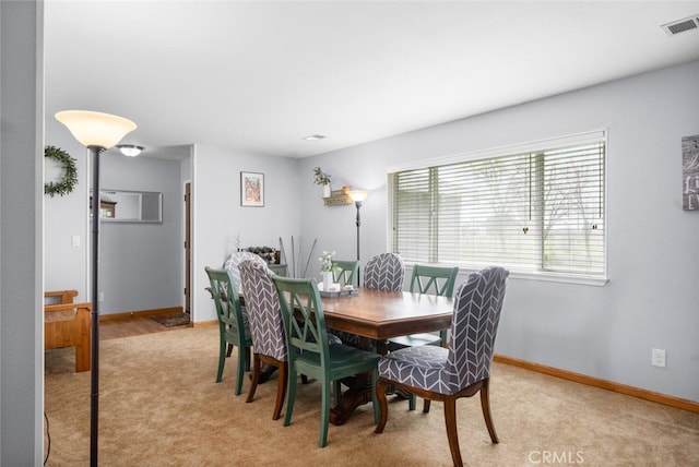 dining area with light colored carpet, visible vents, and baseboards