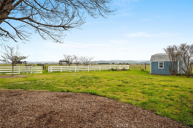 view of yard featuring an outdoor structure, a shed, fence, and a rural view