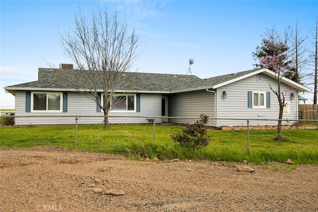 ranch-style home featuring a chimney, a front yard, fence, and roof with shingles