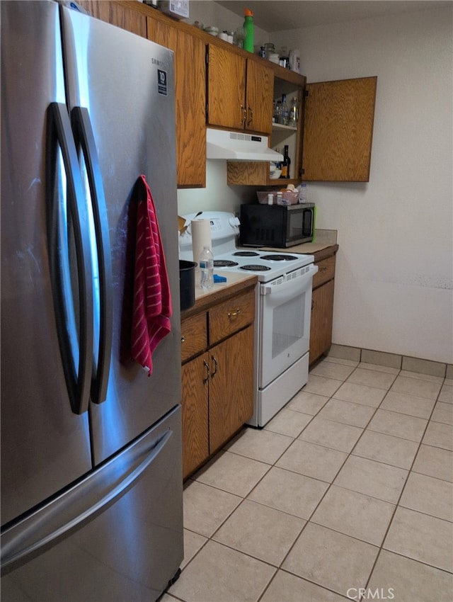 6613 Sunnyhill Rd, Joshua Tree, CA 92252 - kitchen with brown cabinets, light tile patterned floors, under cabinet range hood, white electric stove, and freestanding refrigerator