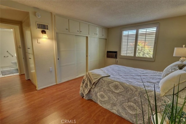bedroom with visible vents, light wood-type flooring, a closet, and a textured ceiling