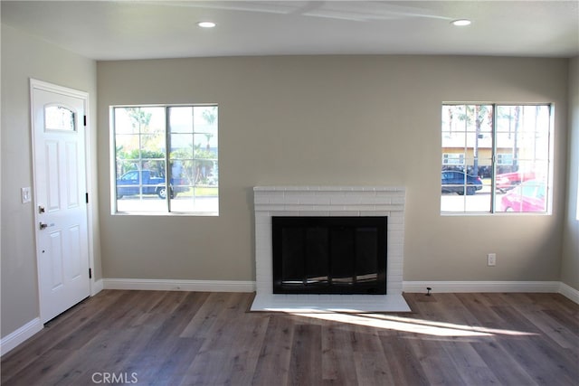 17730 Ivy Ave, Fontana, CA 92335 - unfurnished living room featuring wood finished floors, a brick fireplace, a healthy amount of sunlight, and baseboards