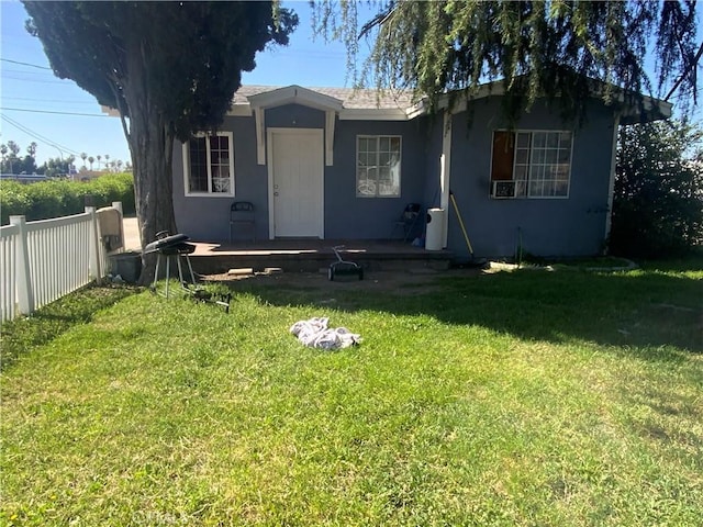 view of front facade featuring stucco siding, fence, and a front lawn
