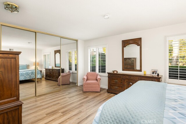 bedroom with light wood-style floors, baseboards, and a closet