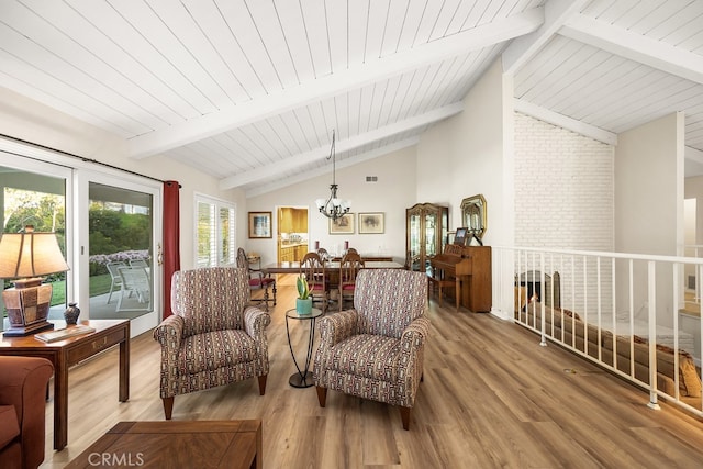 sitting room with vaulted ceiling with beams, wood finished floors, an upstairs landing, and an inviting chandelier