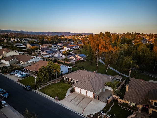 aerial view at dusk featuring a mountain view and a residential view