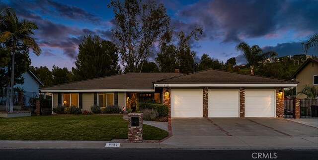 ranch-style house featuring a tiled roof, a garage, a front lawn, and driveway