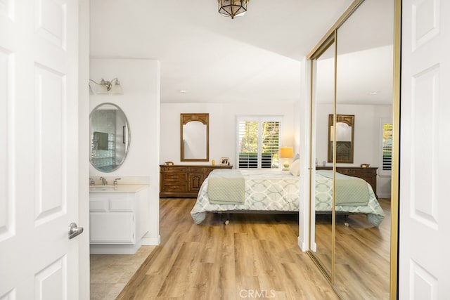 bedroom with a closet, a sink, and light wood-type flooring