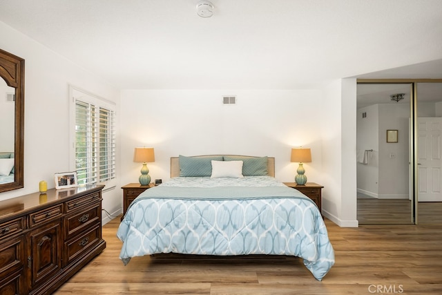bedroom featuring visible vents, light wood-style flooring, and baseboards