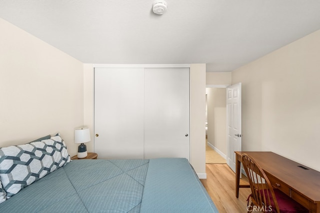 bedroom with baseboards, a closet, and light wood-style flooring