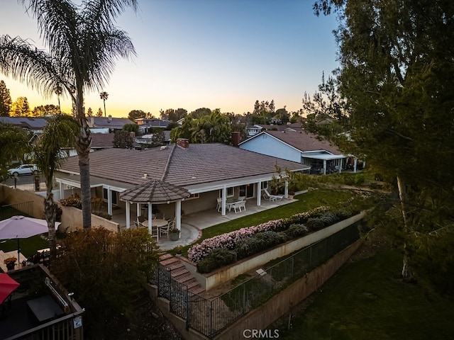 back of property with a tiled roof, a fenced backyard, and a patio area