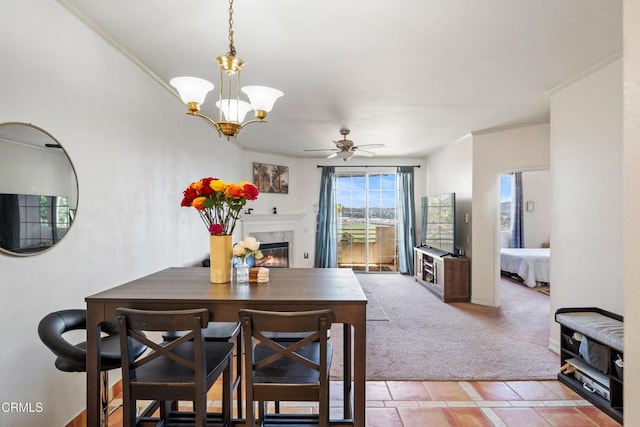 dining area with light colored carpet, ceiling fan with notable chandelier, ornamental molding, and a premium fireplace