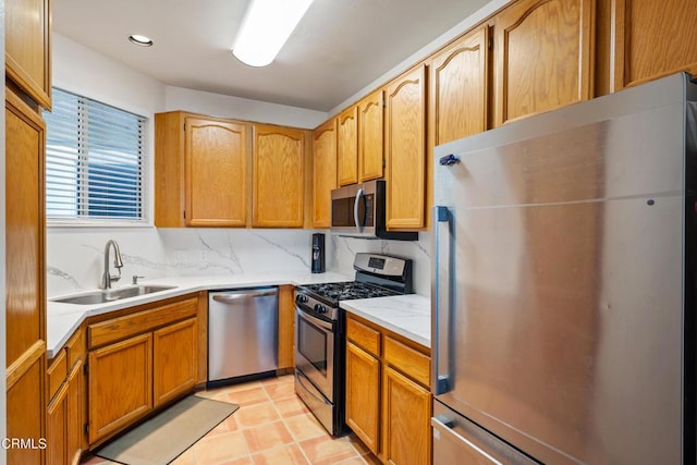 kitchen with light tile patterned floors, a sink, decorative backsplash, light countertops, and appliances with stainless steel finishes