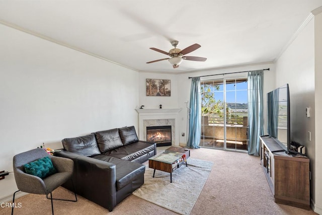 living area with baseboards, carpet floors, a high end fireplace, ornamental molding, and ceiling fan