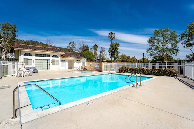 community pool featuring a community hot tub, a patio area, and fence