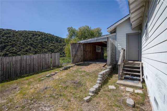 view of yard featuring an attached carport, fence, and entry steps